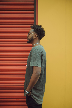 man in gray t-shirt standing near red roll up door