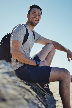 smiling man sitting on gray rock at daytime